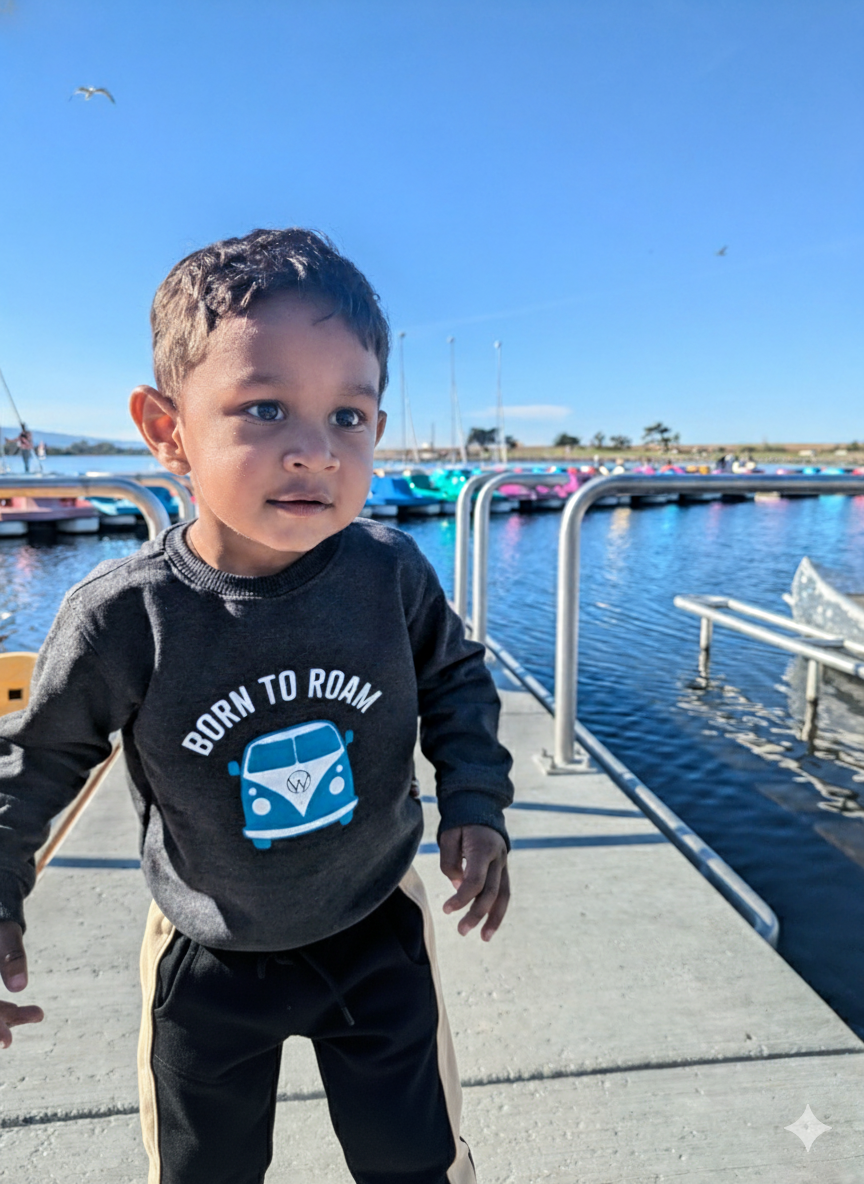 Child wearing a 'Born to Roam' sweatshirt at a marina