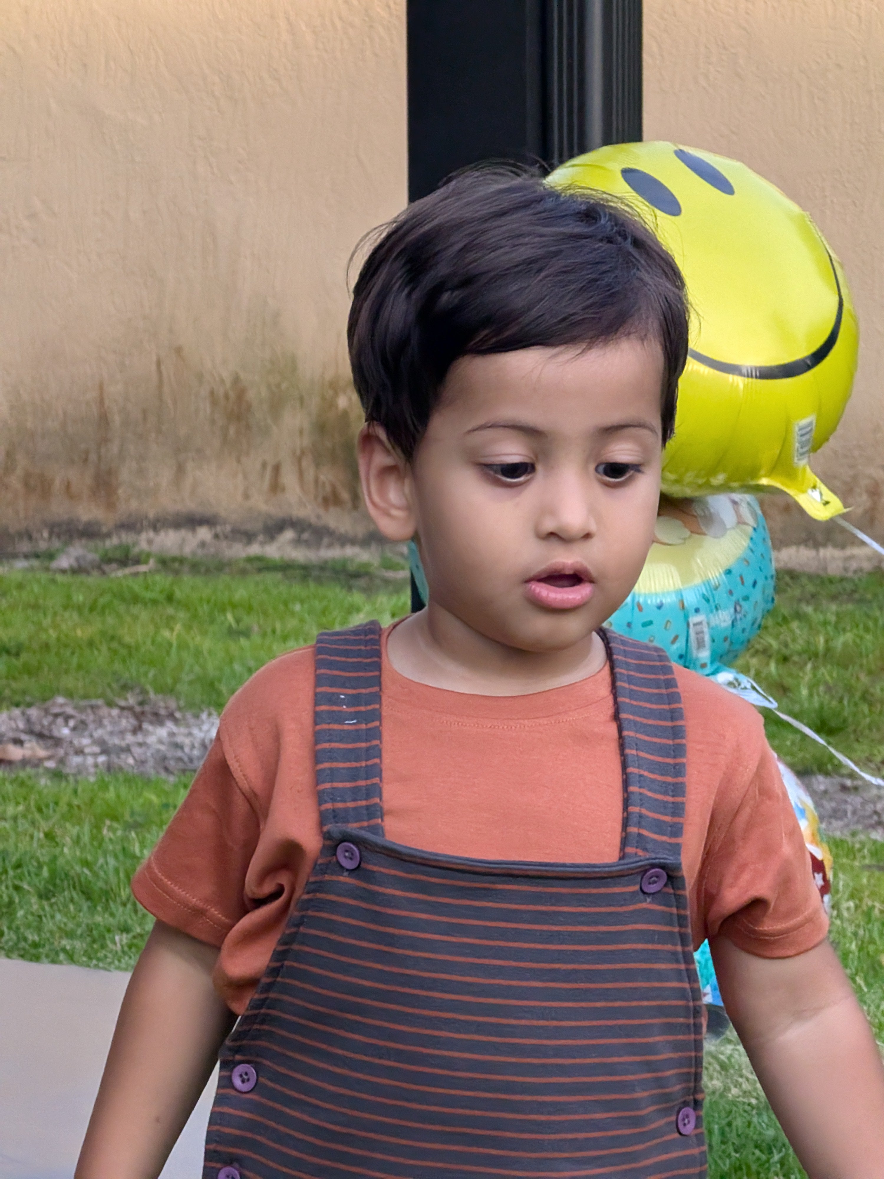 Toddler wearing MulmulBaby Burnt Orange Stripes organic cotton dungaree overalls set over an orange tee, outdoors