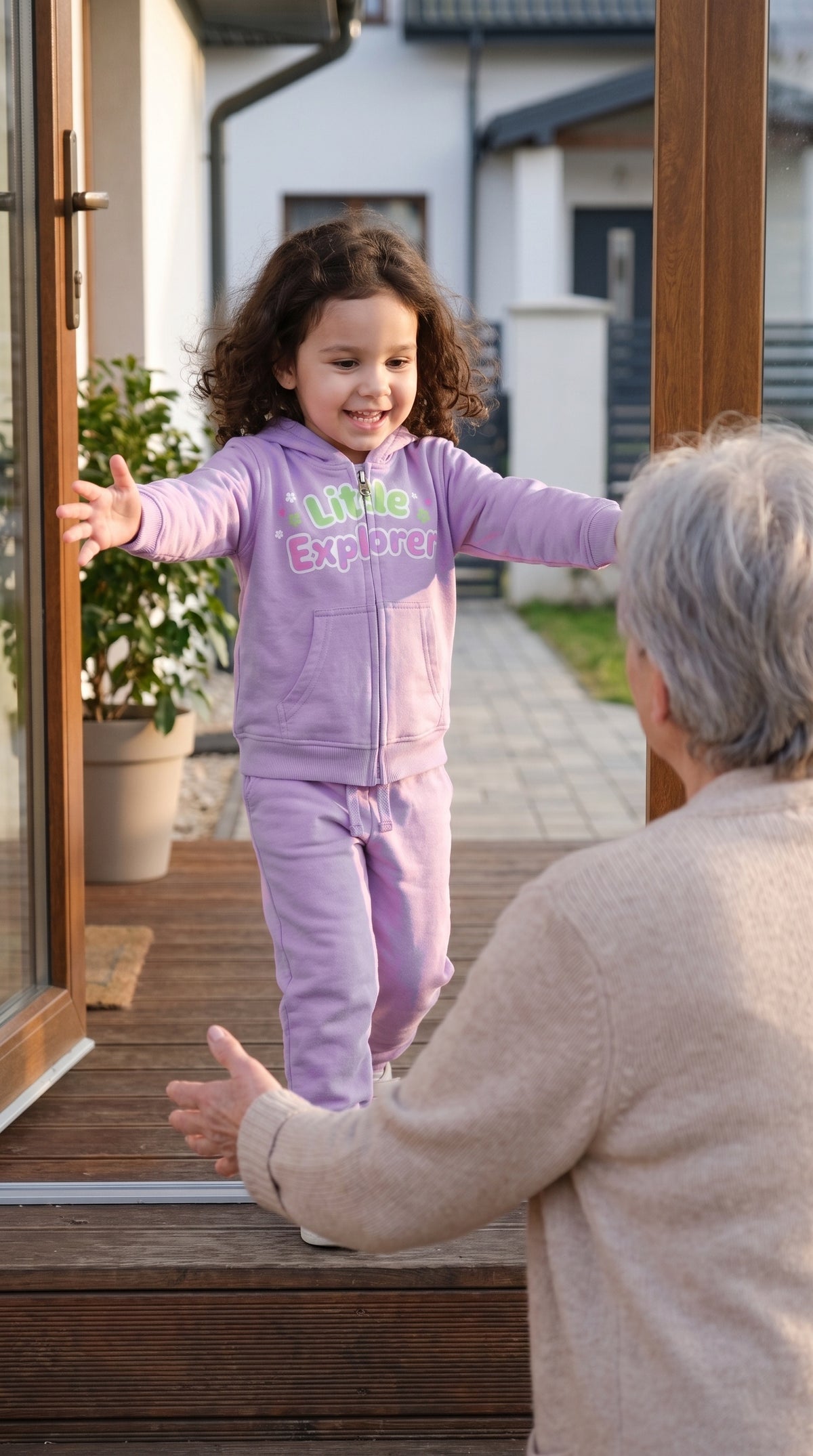 Child in the lavender zip hoodie and jogger set running to a grandparent at the door
