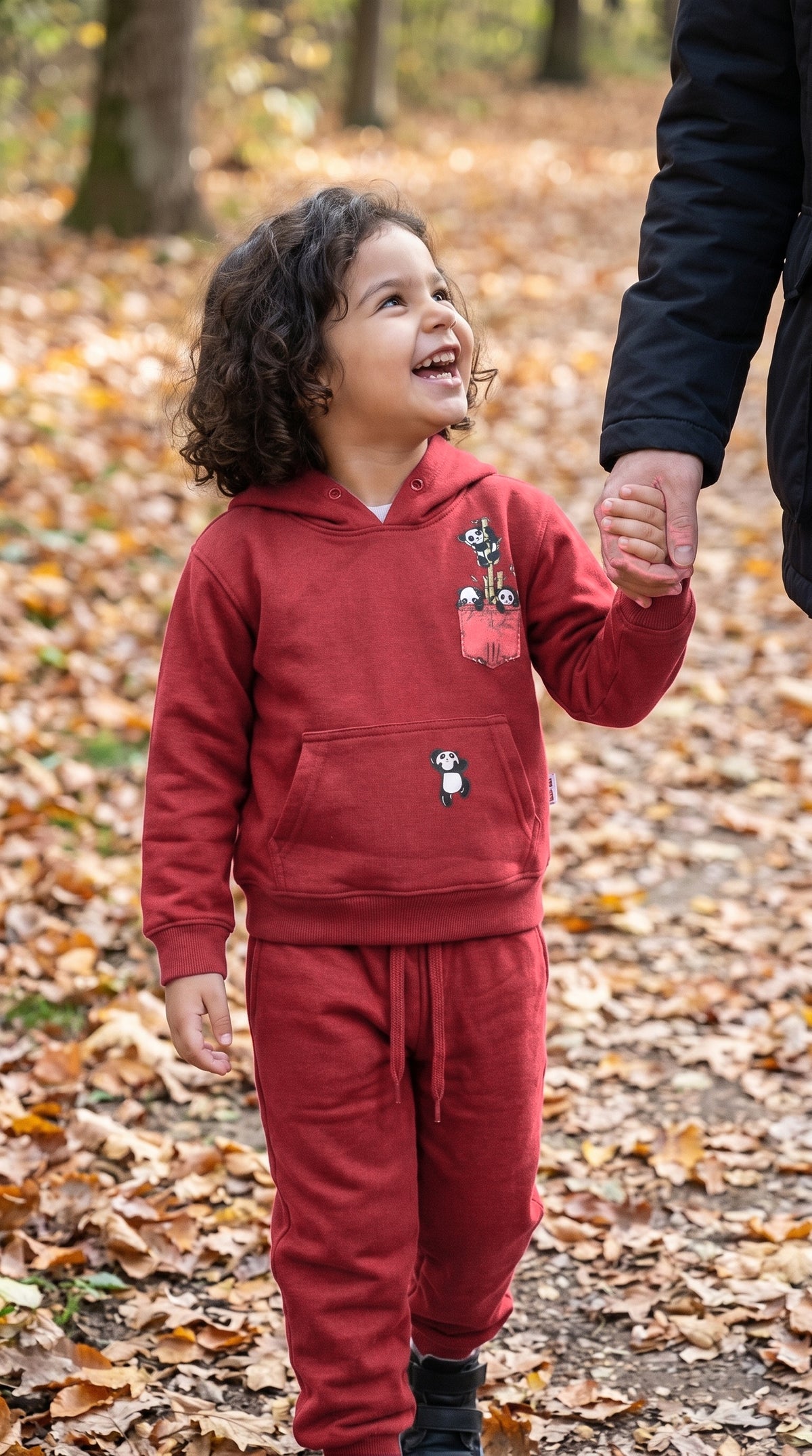 Child in the red hoodie and jogger set walking in autumn leaves