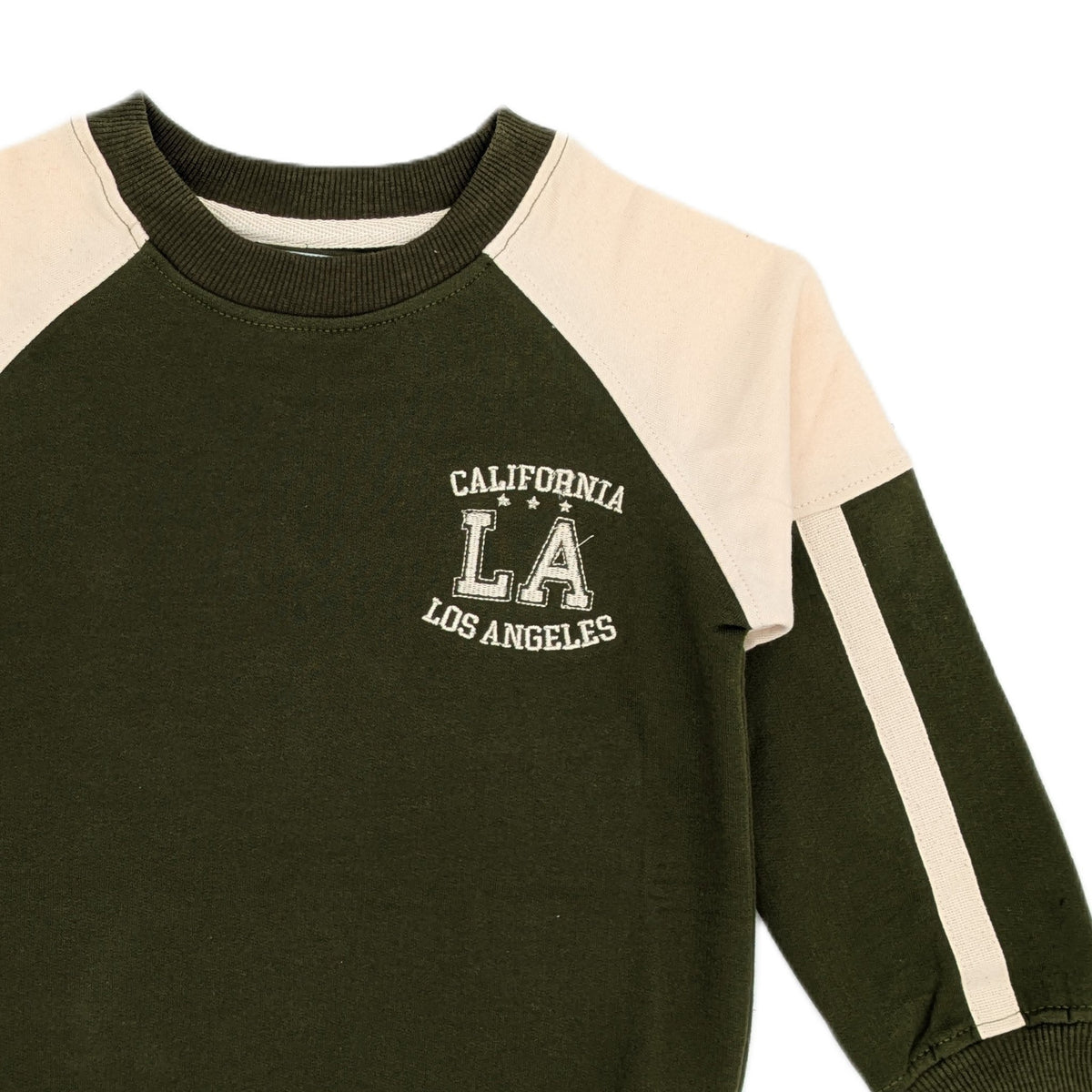 Close view of the olive green raglan sweatshirt showing the beige raglan seam running from the underarm to the neckline, the beige stripe down the sleeve, the ribbed crew neck and the printed CALIFORNIA LA LOS ANGELES chest graphic.