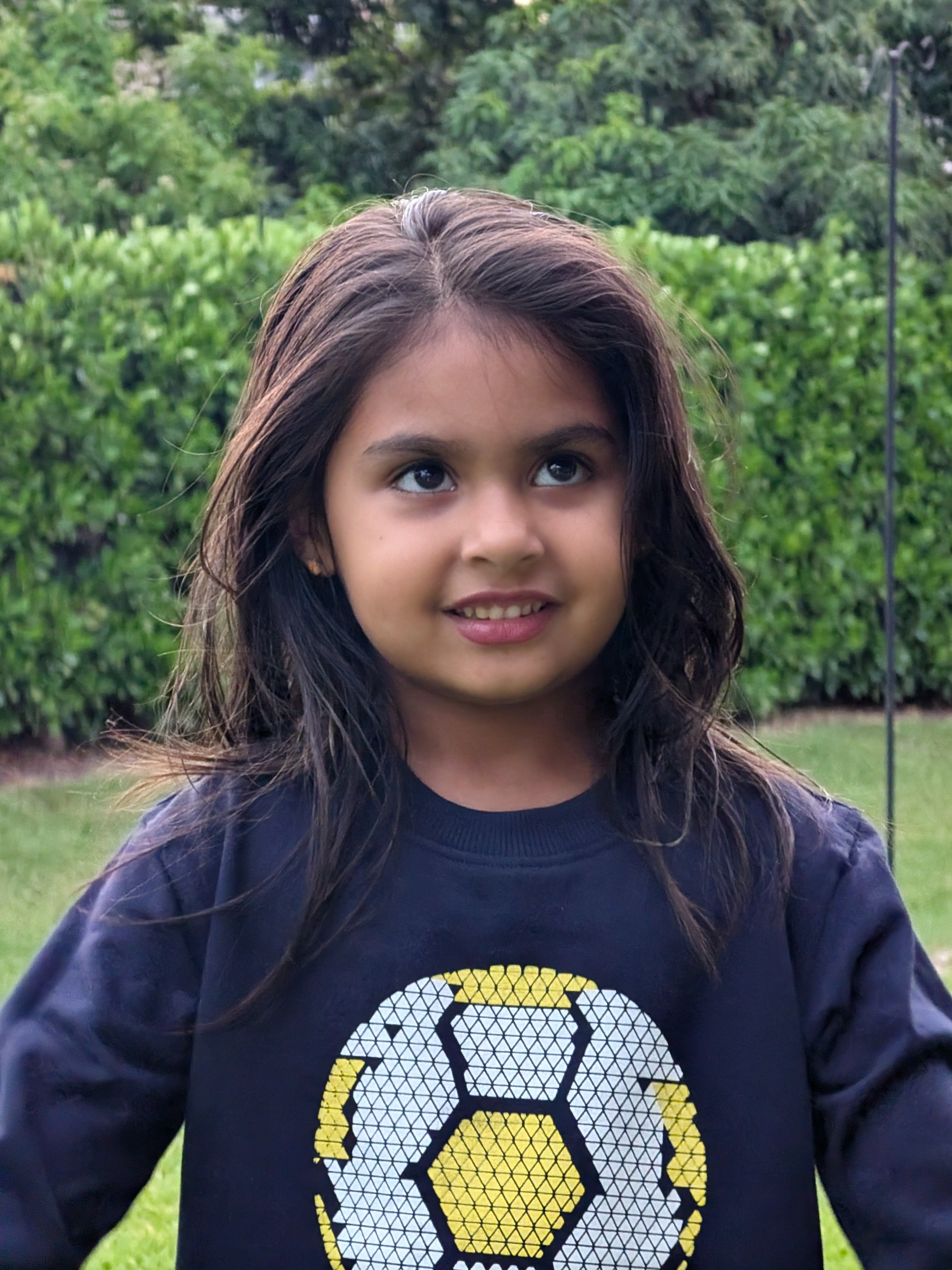Child wearing MulmulBaby navy Soccer Time organic cotton sweatshirt in a garden