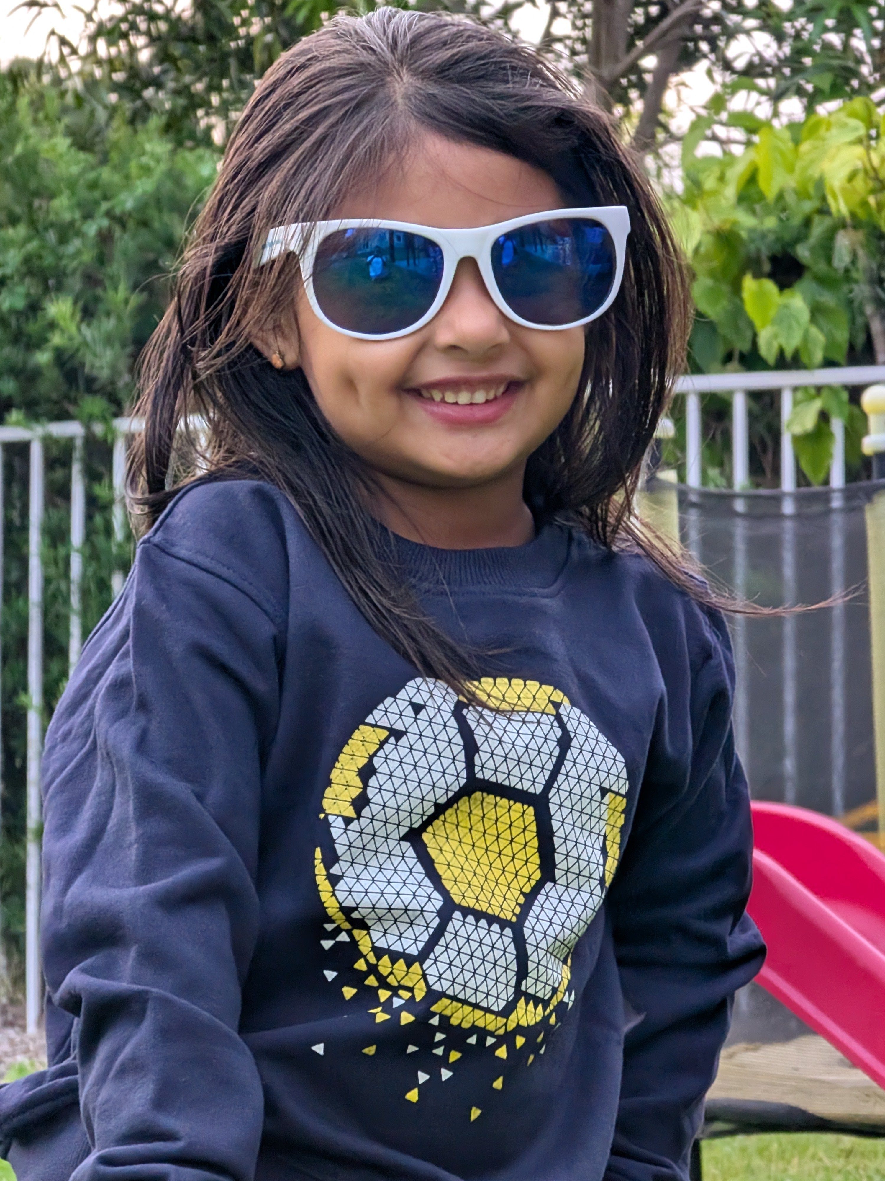 Smiling child in MulmulBaby Soccer Time sweatshirt and sunglasses playing outside